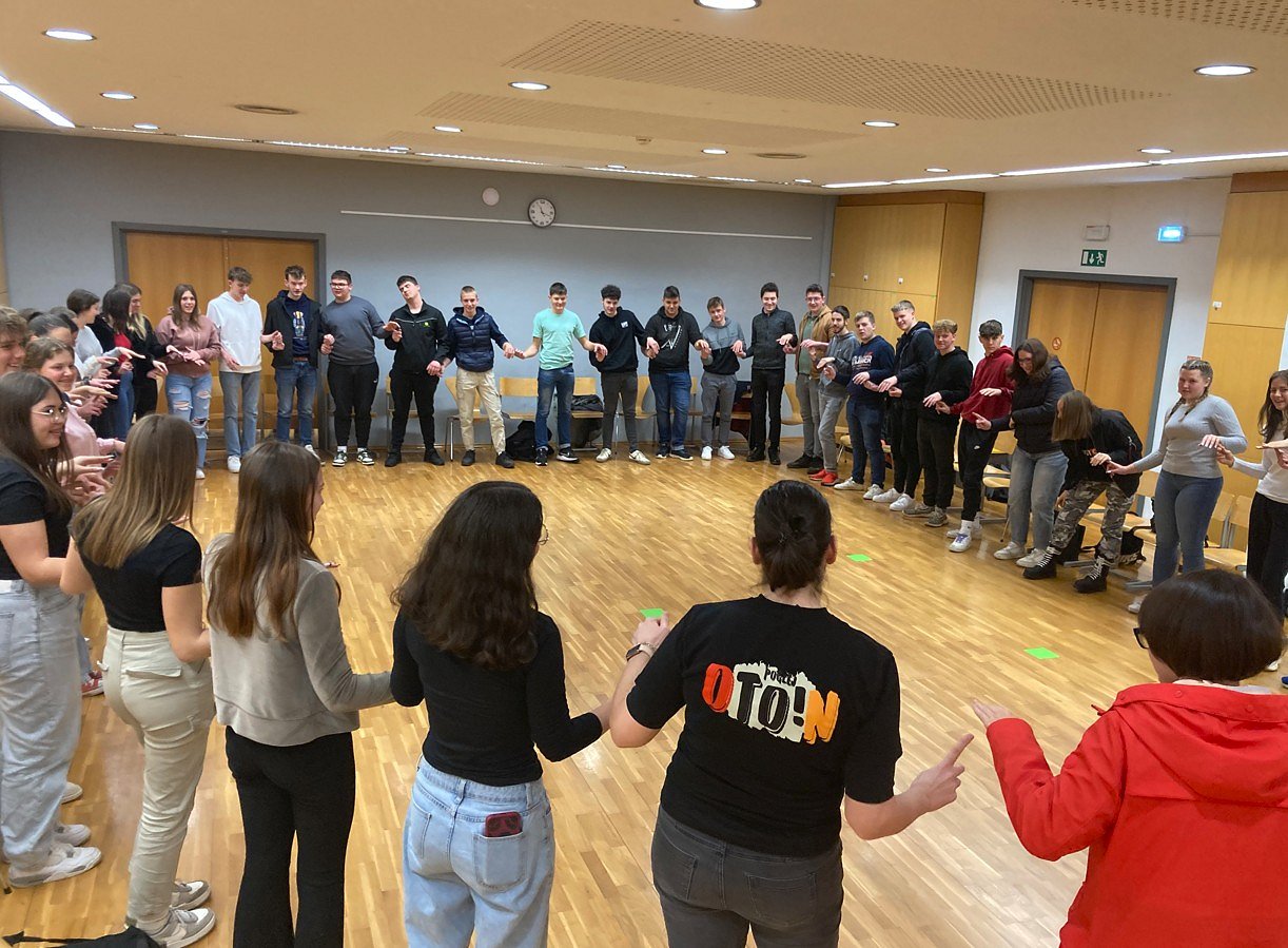 udeleženci stojijo v krogu in se držijo za roke