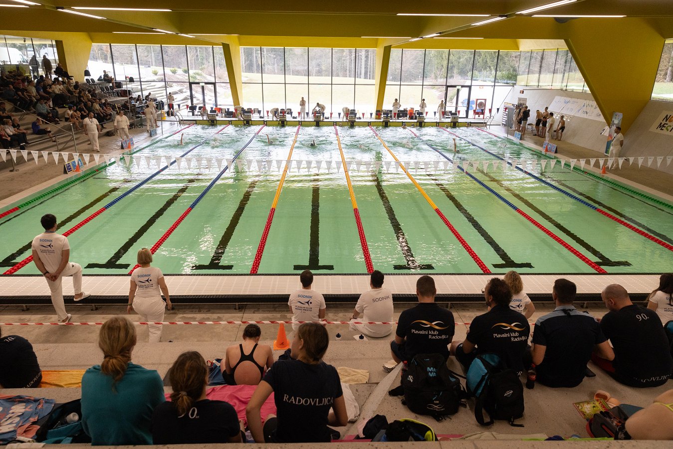 gledalci s tribun spremljajo tekmovanje plavalcev v Bazenu Novo mesto