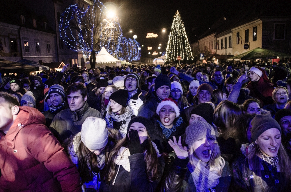 Razigrana publika na Glavnem trgu, v ozadju okrašeno Novo mesto.